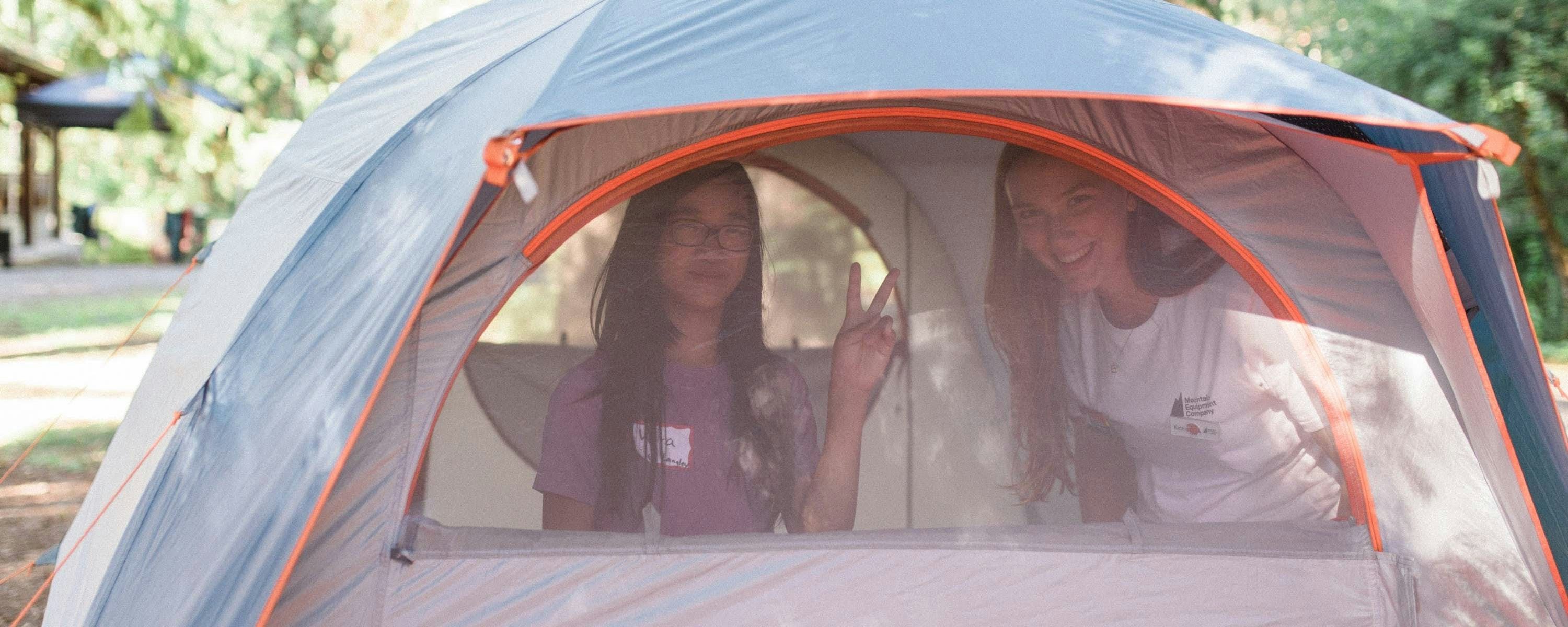 Two campers in a blue and white tent