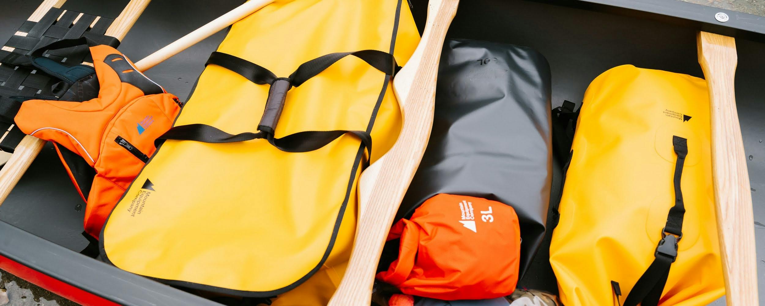 Dry bags, a duffle and a PFD in a canoe