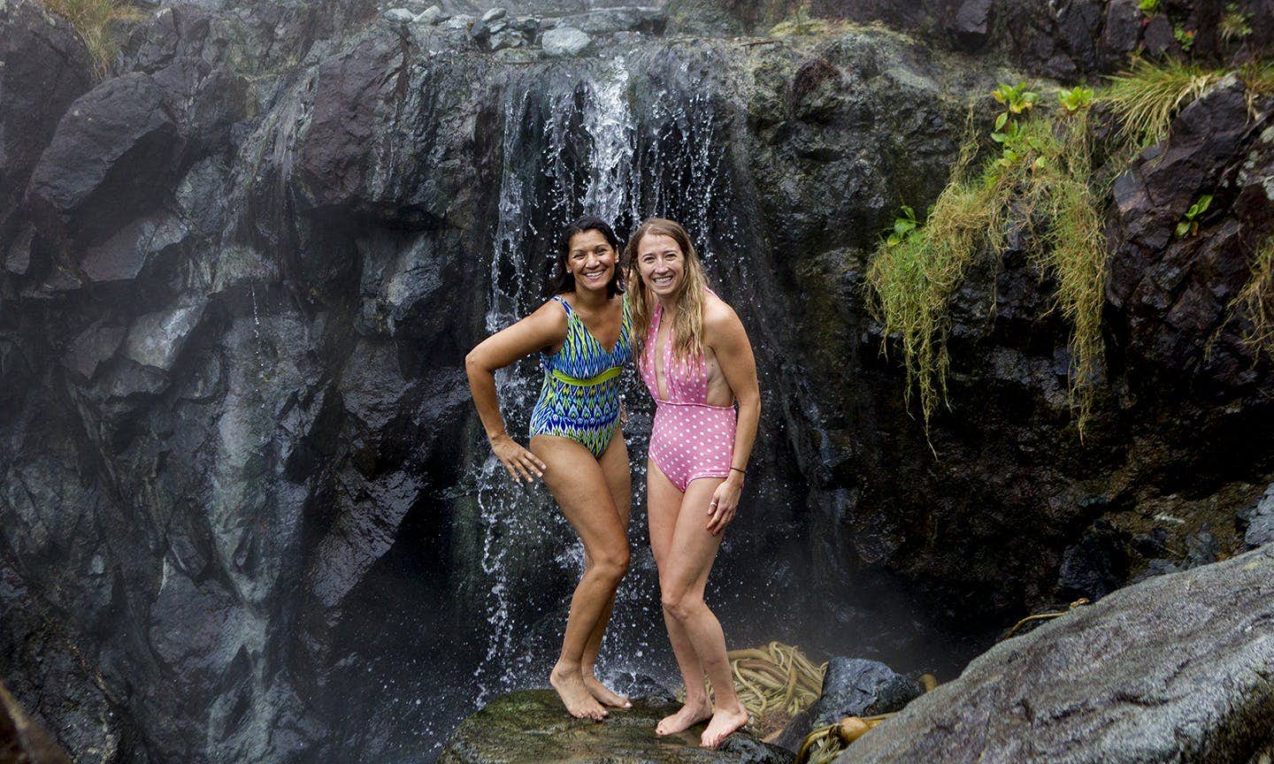 Two people standing in front of a rocky waterfall, smiling