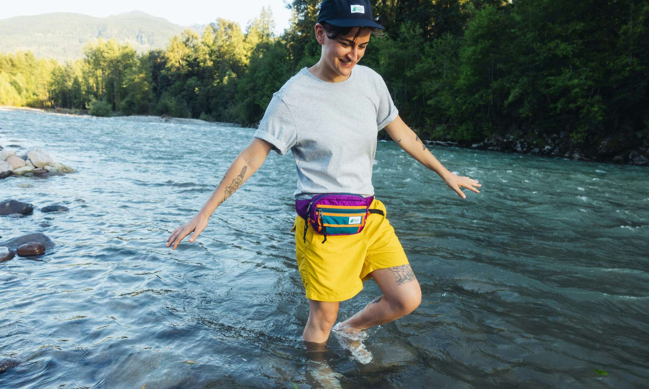 A person wearing a brightly coloured Hip Pack wading in a river