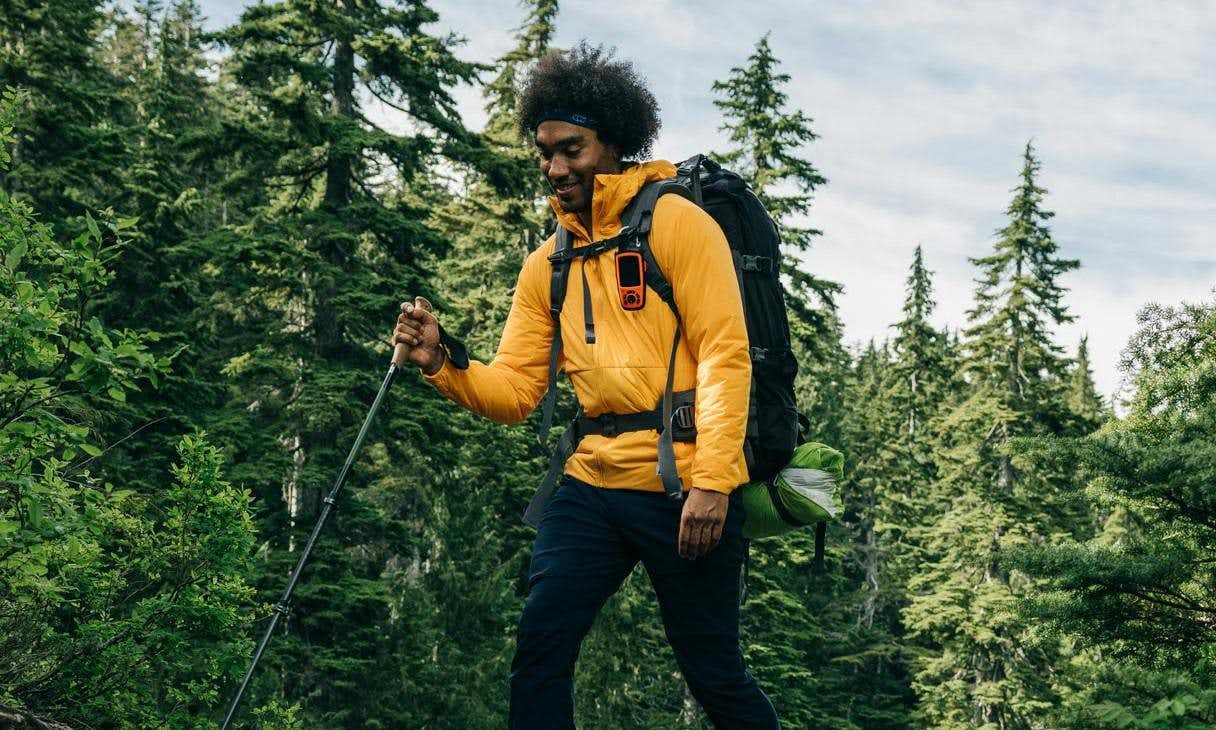 Hiker wearing a yellow hooded mid-layer and a black backpack in the forest