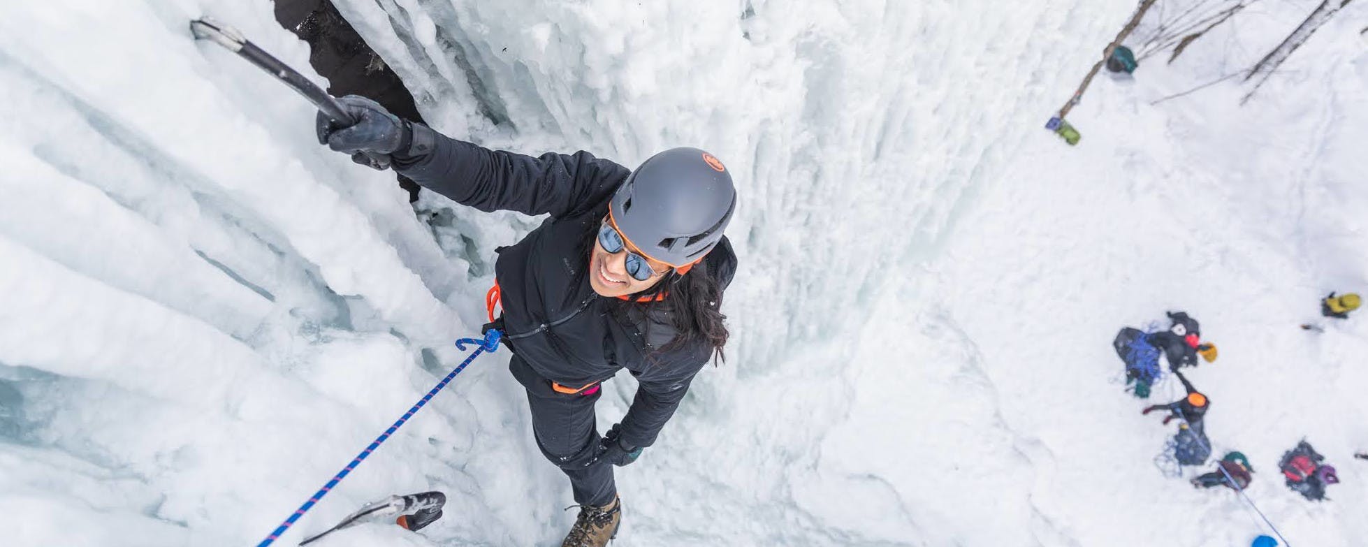 Explorer climbing up a mountain of ice with black climbing gear