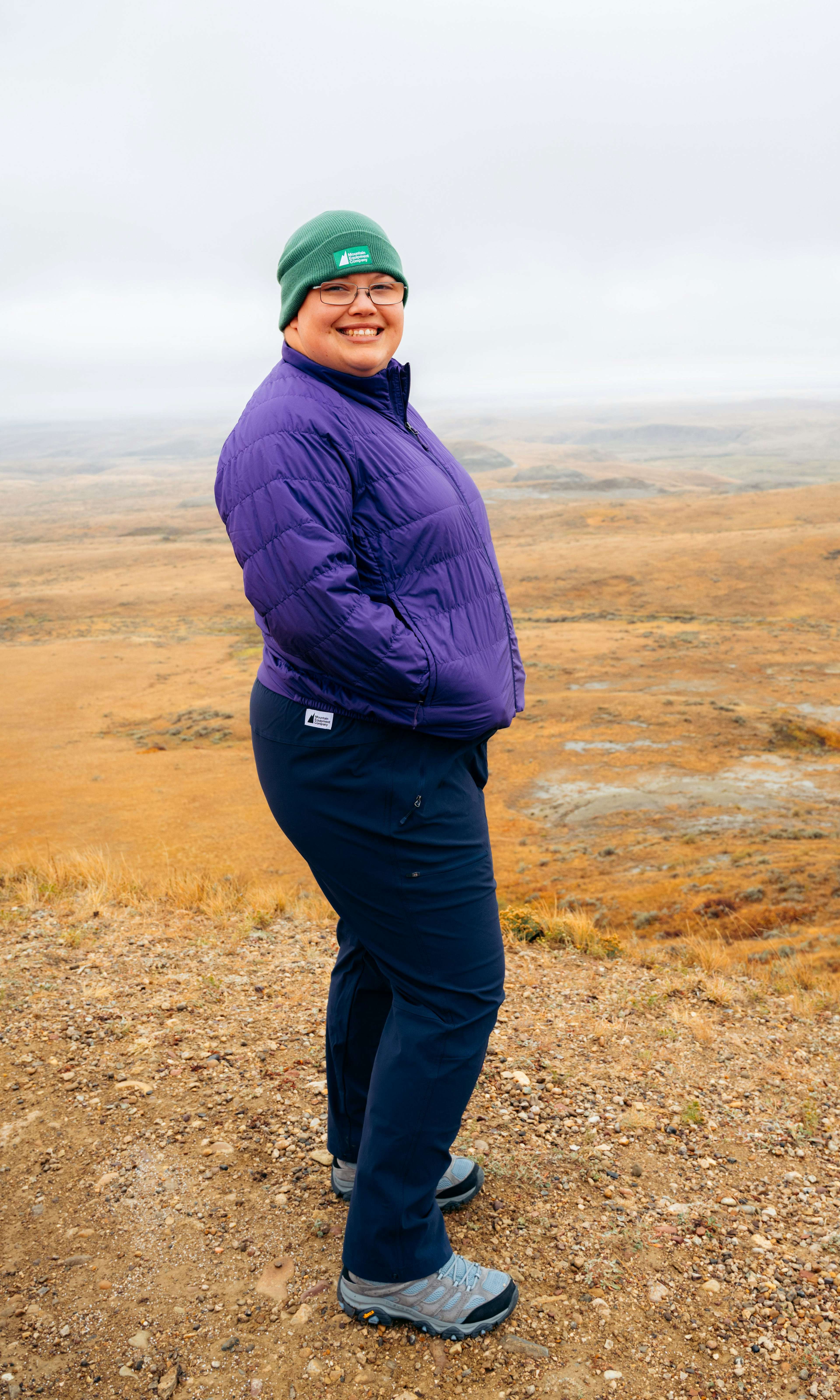 Rebecca, au Parc national des Prairies, portant la tuque édition Classiques de MEC en vert, le manteau Uplink de MEC et le pantalon Borderland de MEC en noir.