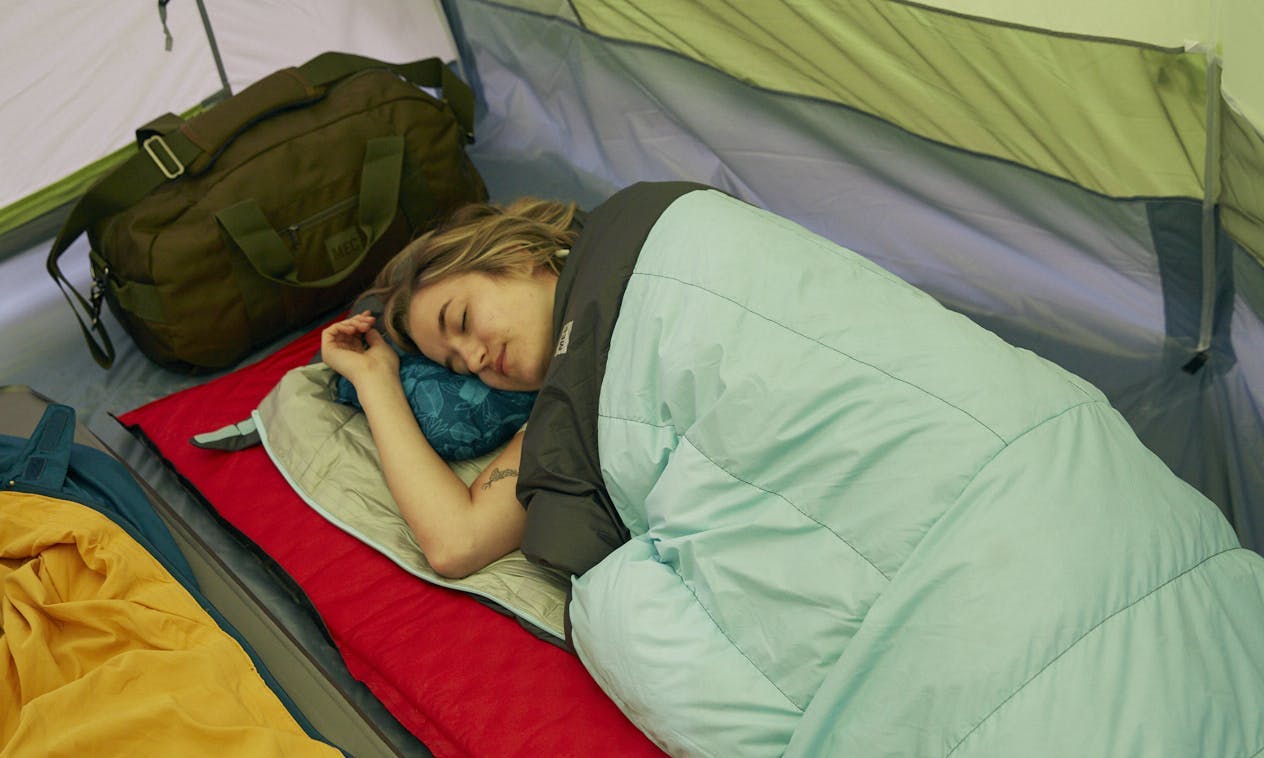 Person sleeping in a down sleeping bag in a tent