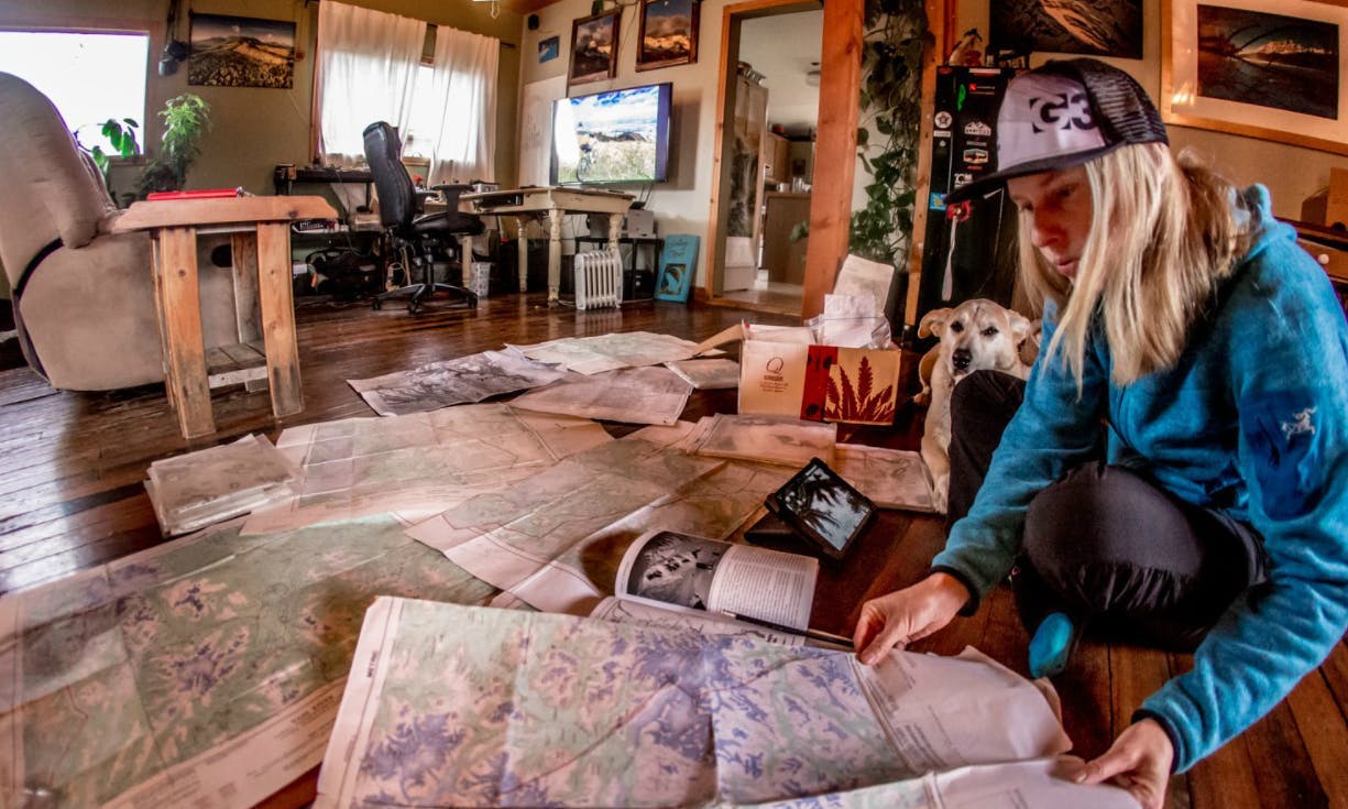 A woman pores over maps in a cozy living room.