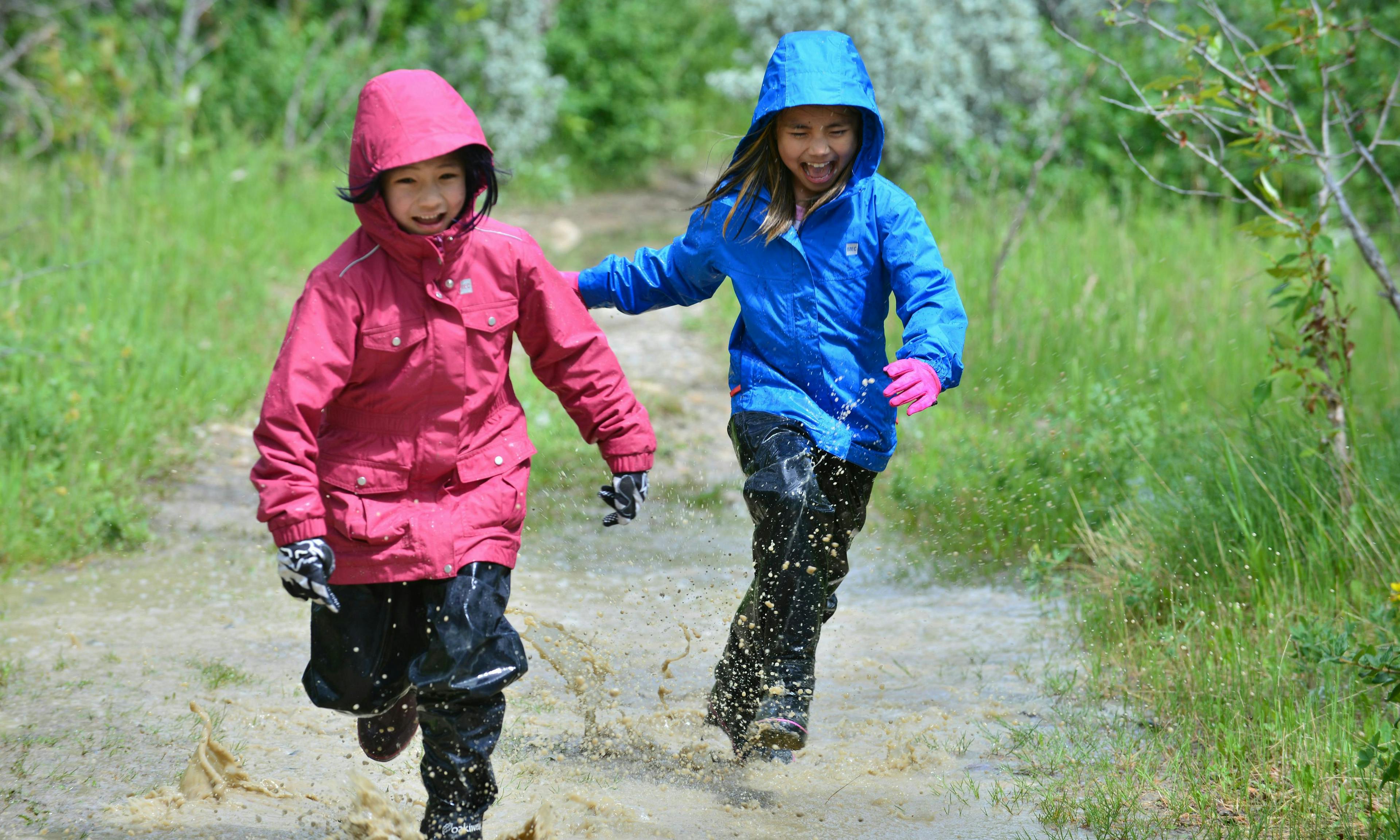 Two kids running through a puddle