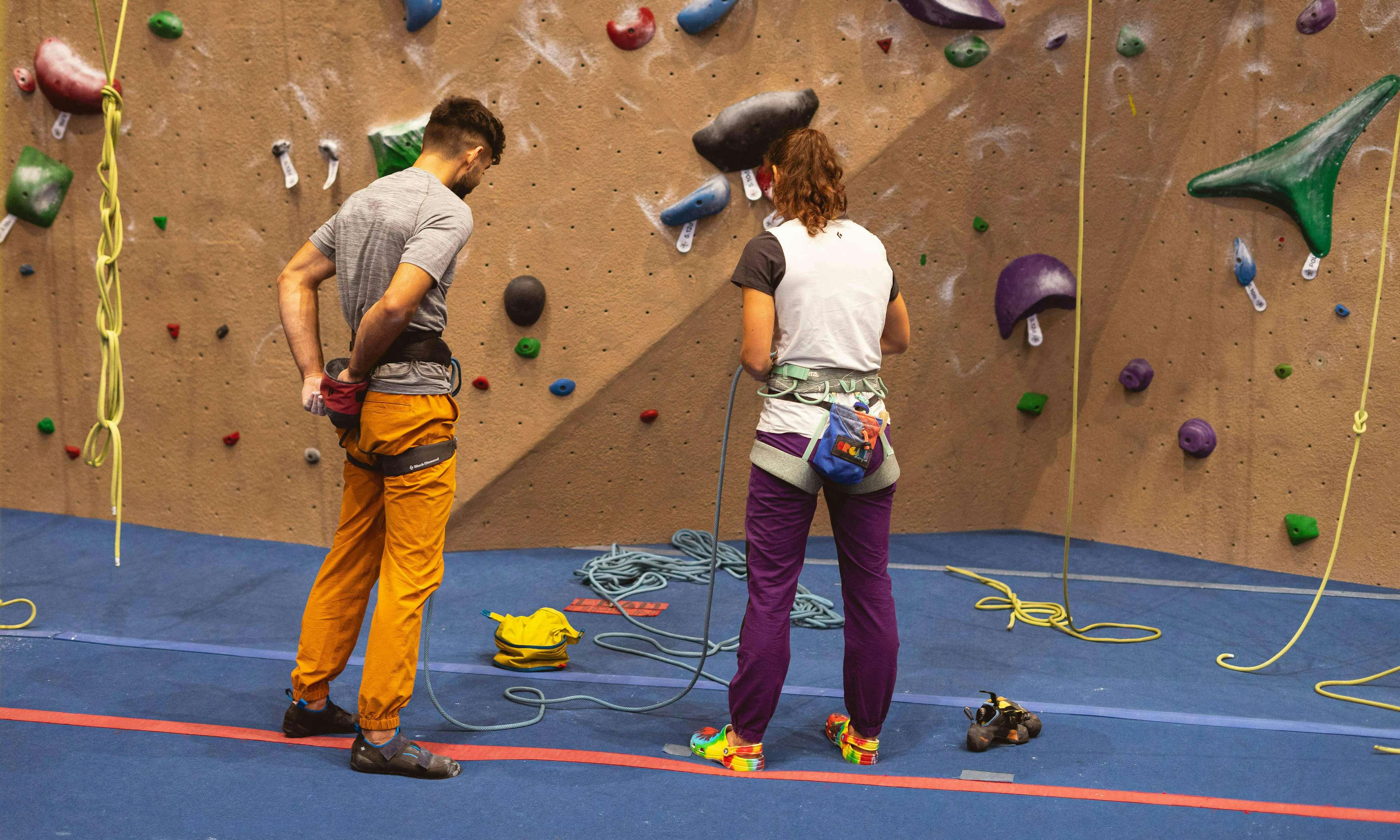 Two climbers in gym, one wearing slip on sandals