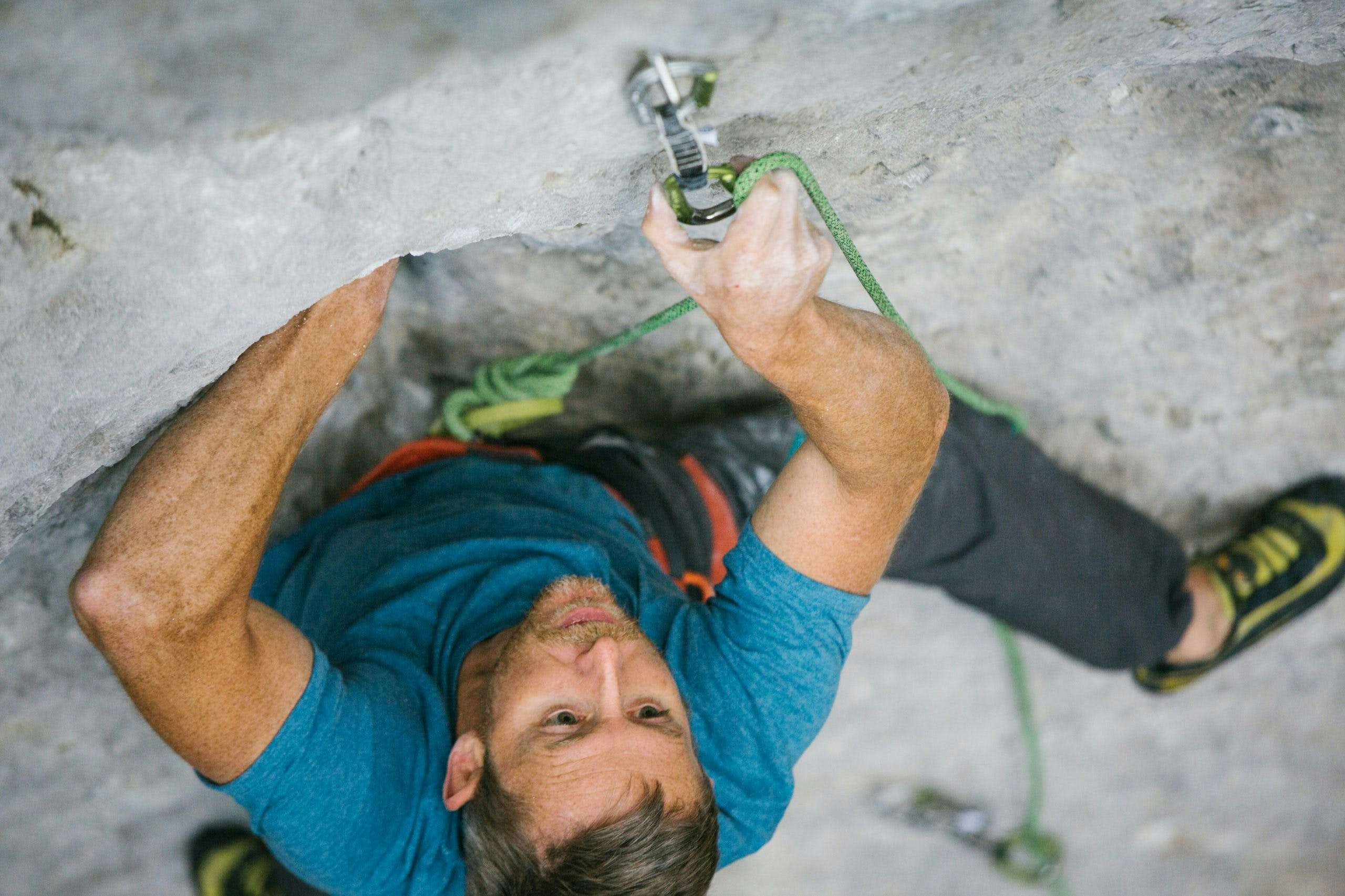 Close up of Tommy Caldwell clipping rope into a quickdraw while climbing