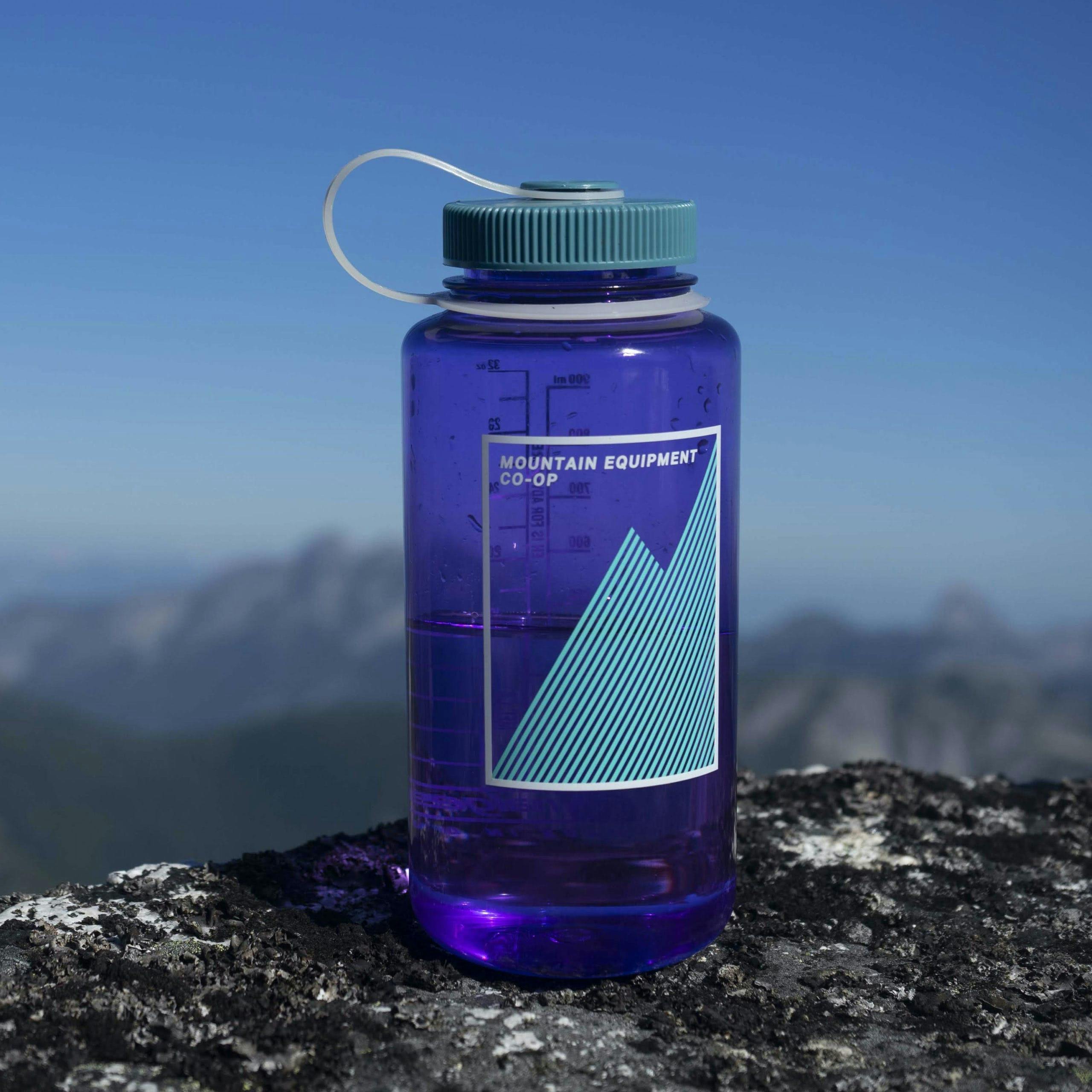 Blue water bottle sitting on a rock with mountain view behind