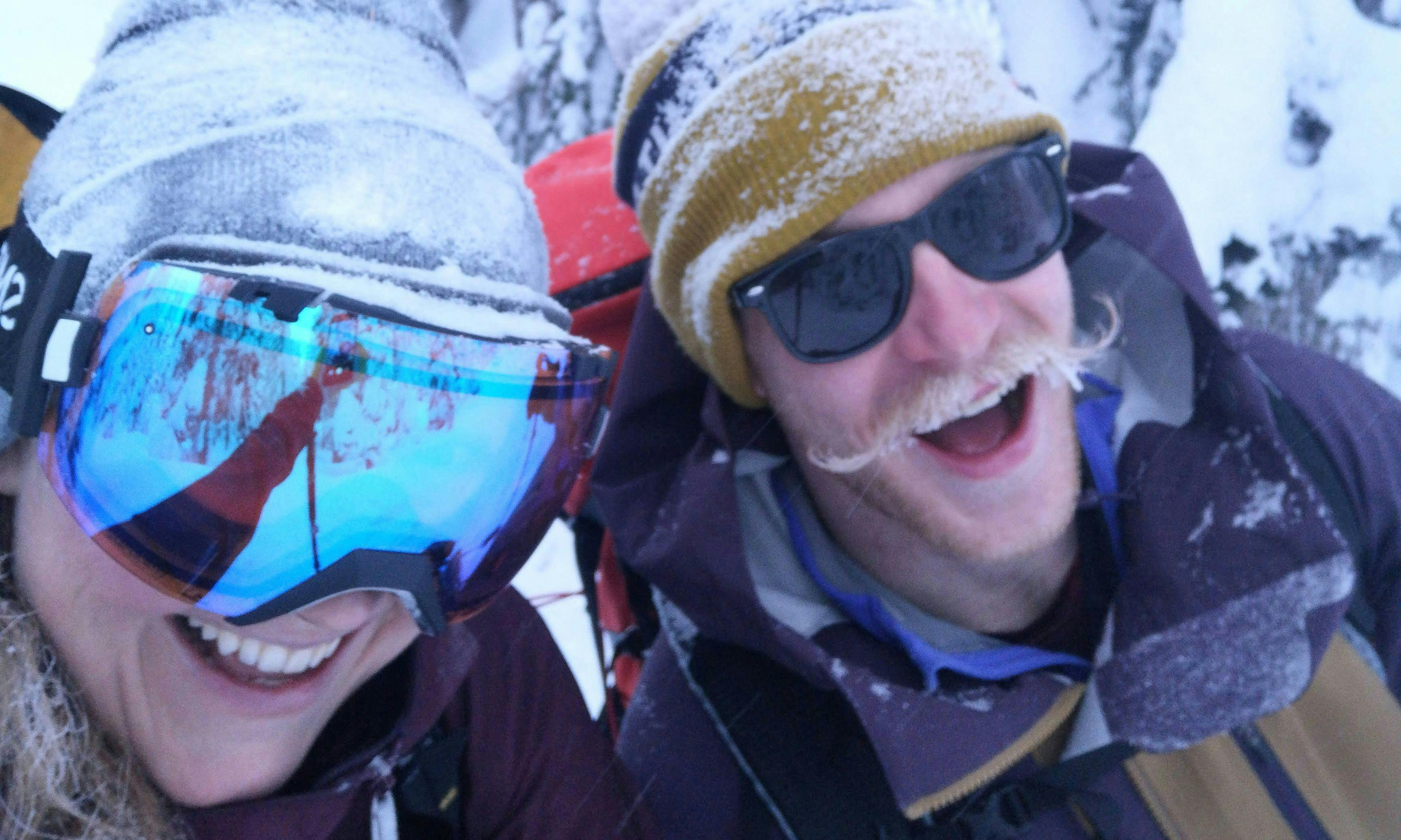 Two skiers, one with a frosty mustache and the other wearing goggles