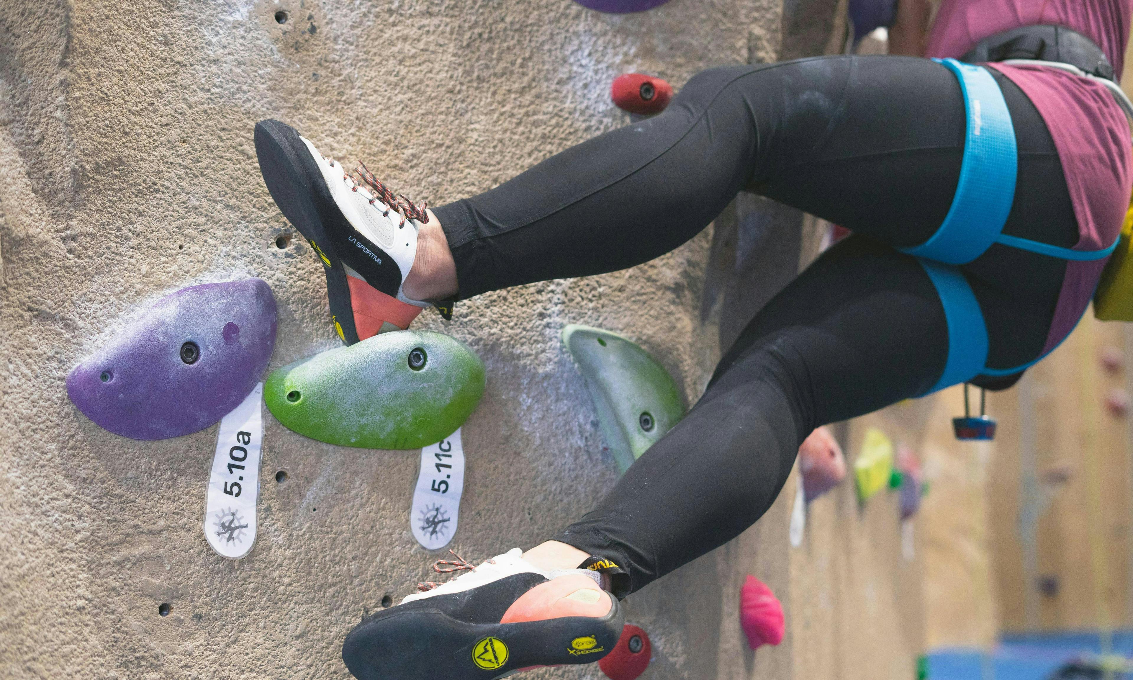 Close up of climbing shoes on a hold with grades on it