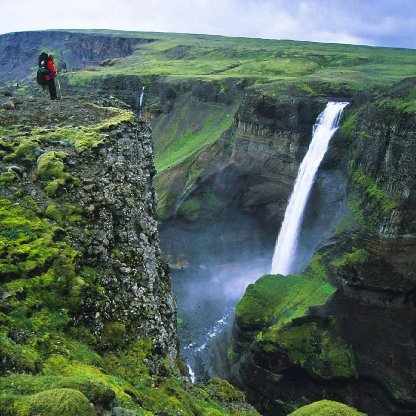 Hiker in Iceland looking at a beautiful waterfall