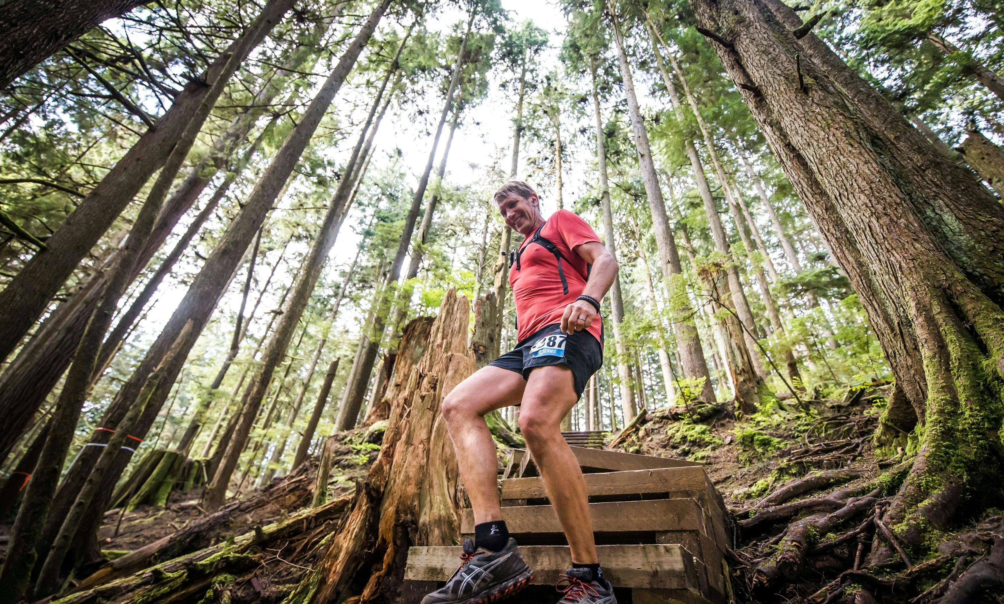 A trail runner descends a wooden staircase in the middle of a trail race.