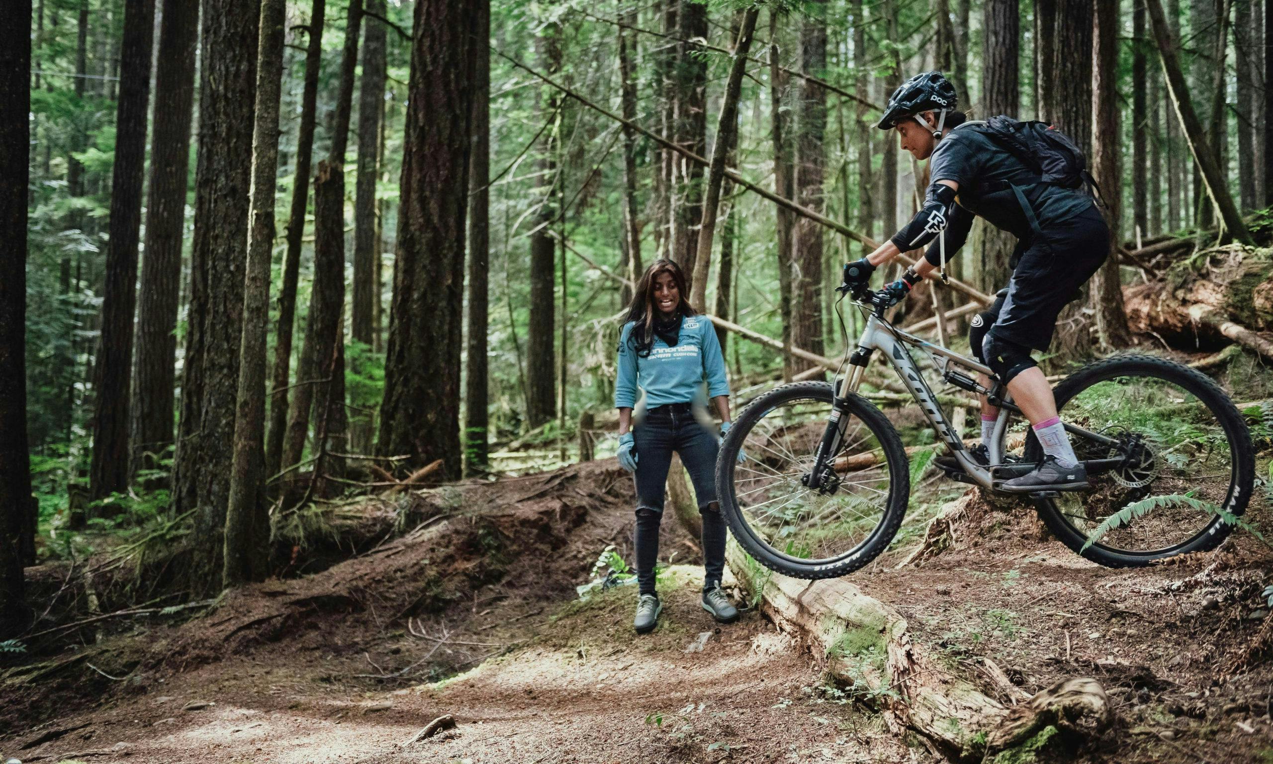 Anita coaching a mountain biker over a drop on a trail