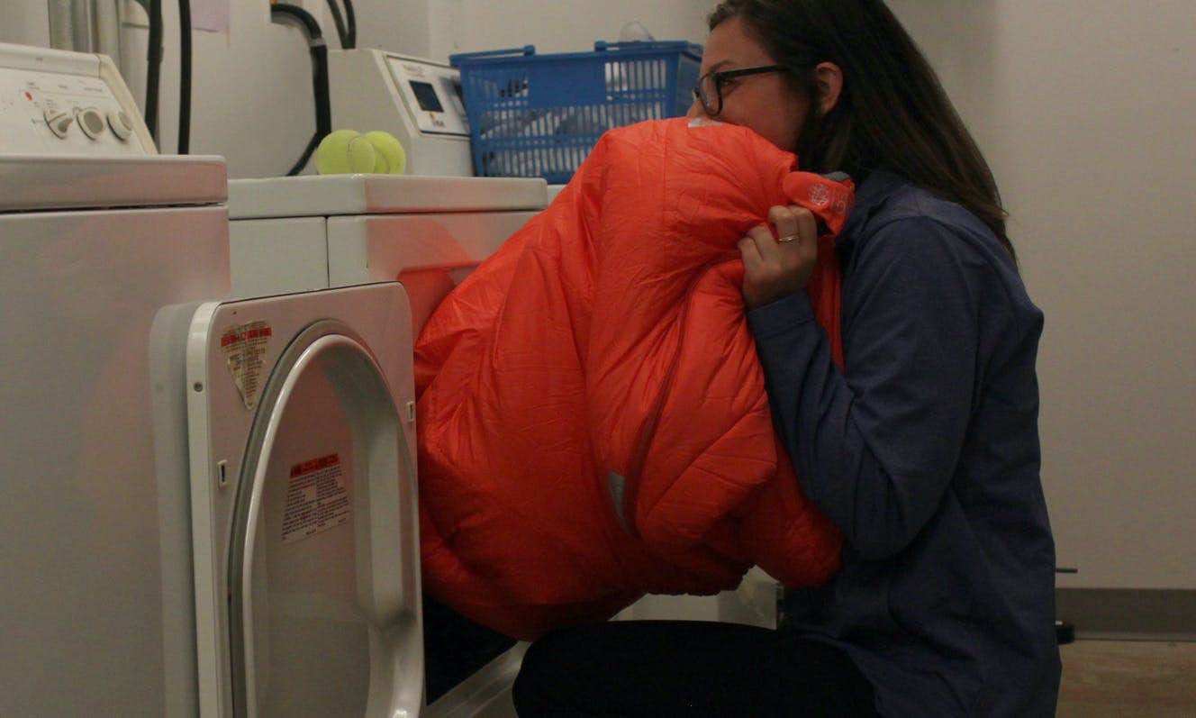 Person pulling a clean sleeping bag out of the dryer