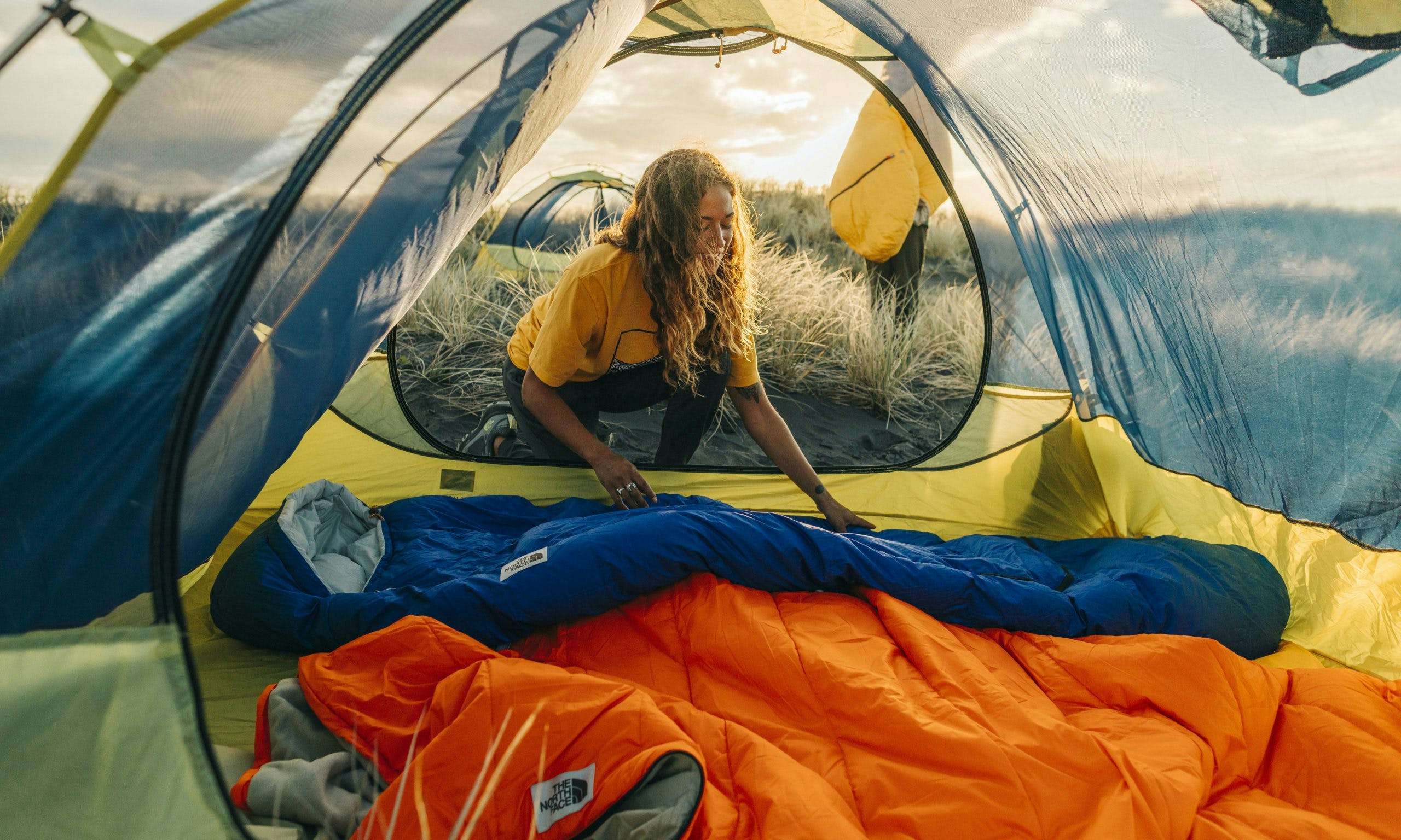 Camper arranging The North Face Eco Trail sleeping bags in a tent