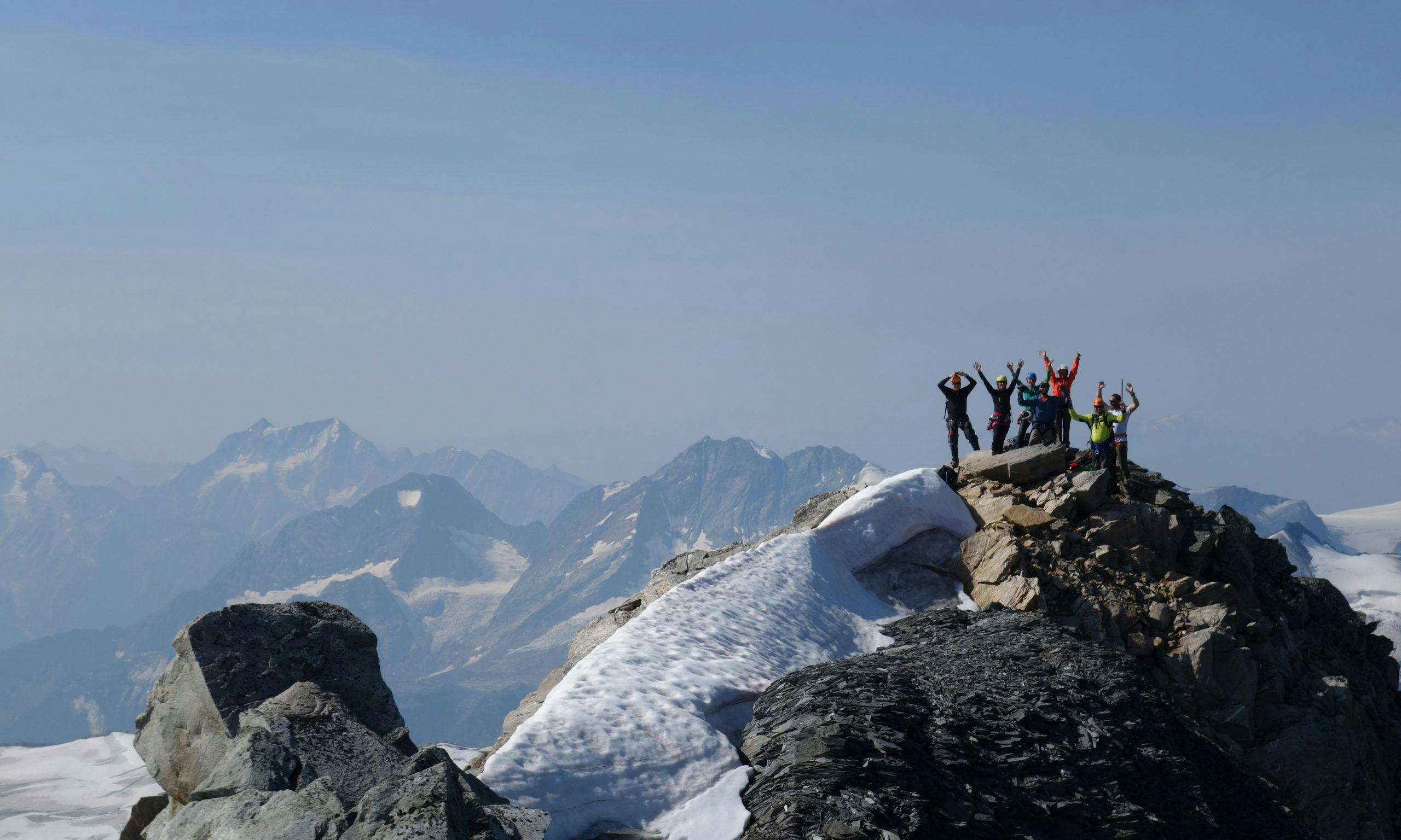 People raising their hands in the distance on a mountaintop