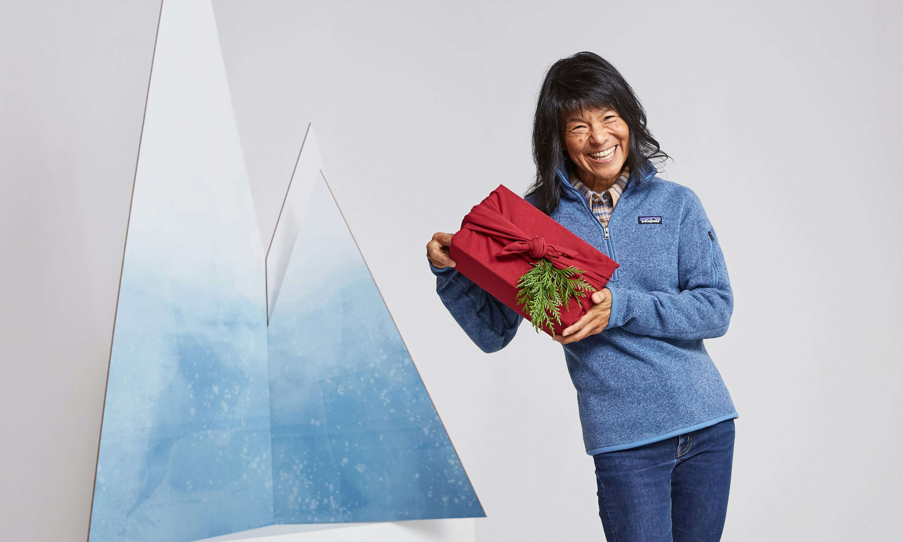 Person holding a present wrapped in fabric with fallen greenery