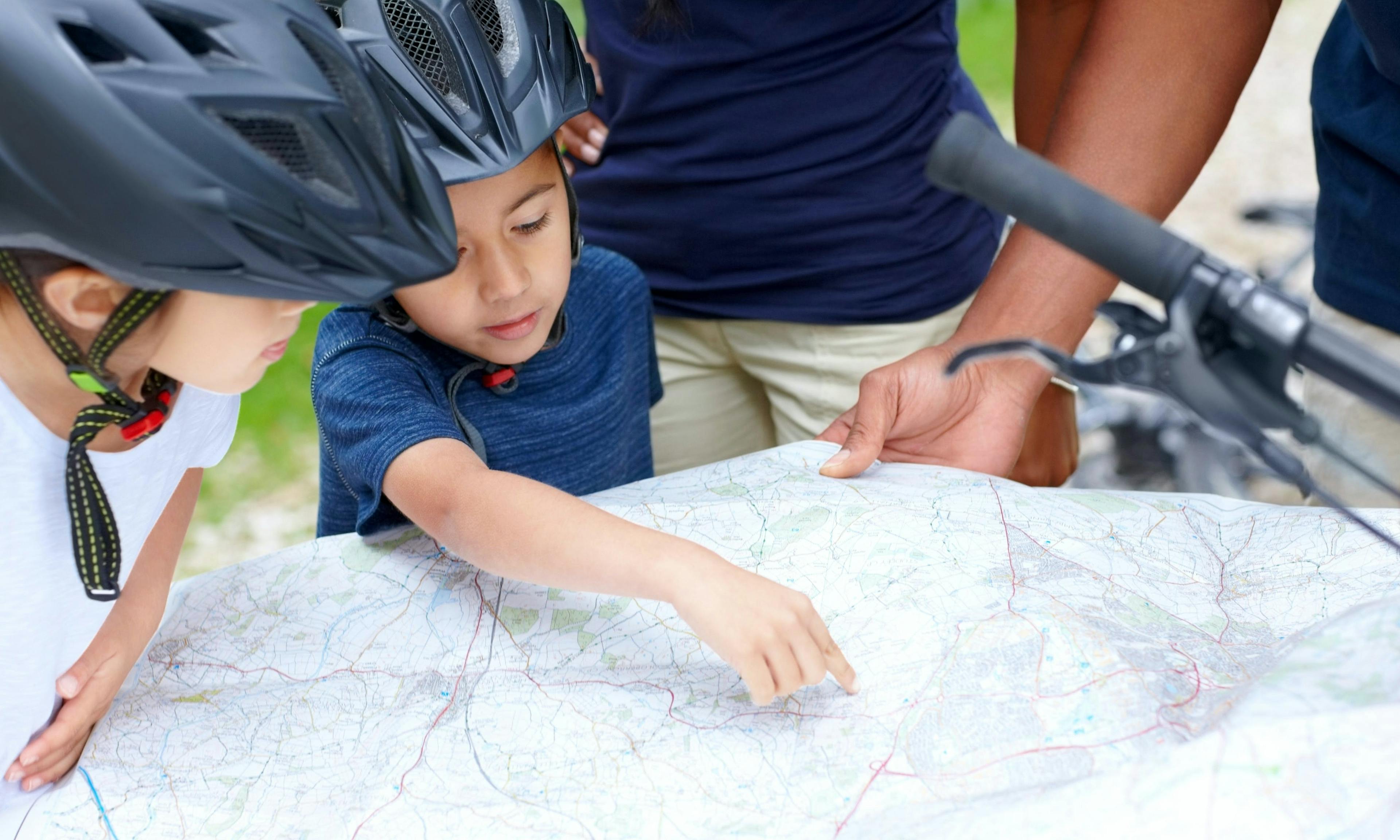 Kid wearing a bike helmet checking out a map