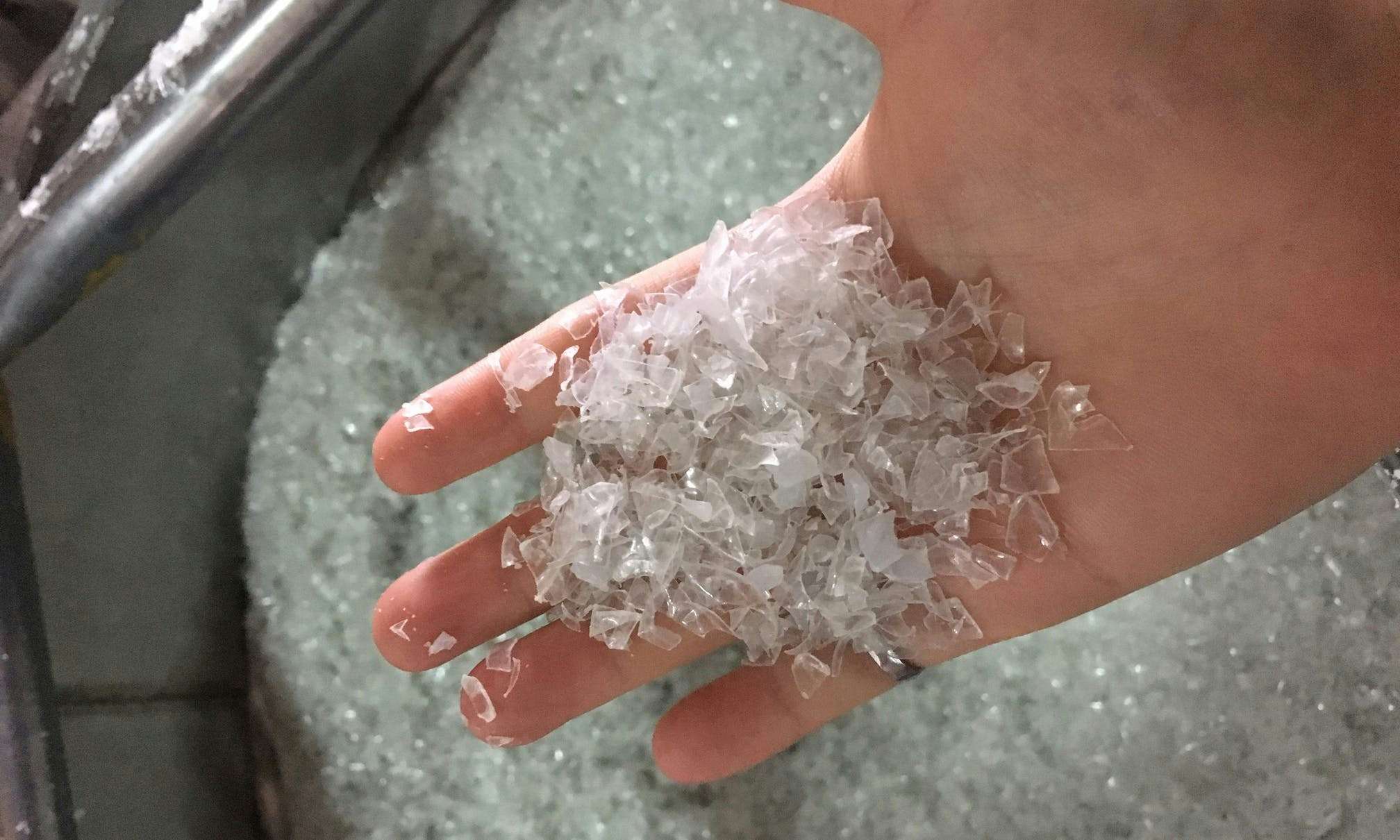 Hand holding small flakes of clear plastic