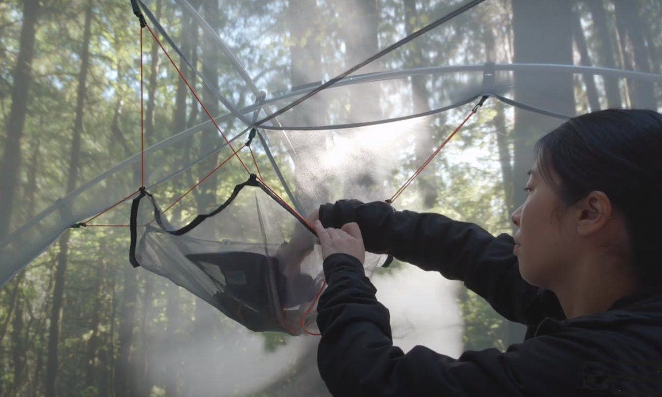 Camper putting gear in a gear loft in a tent