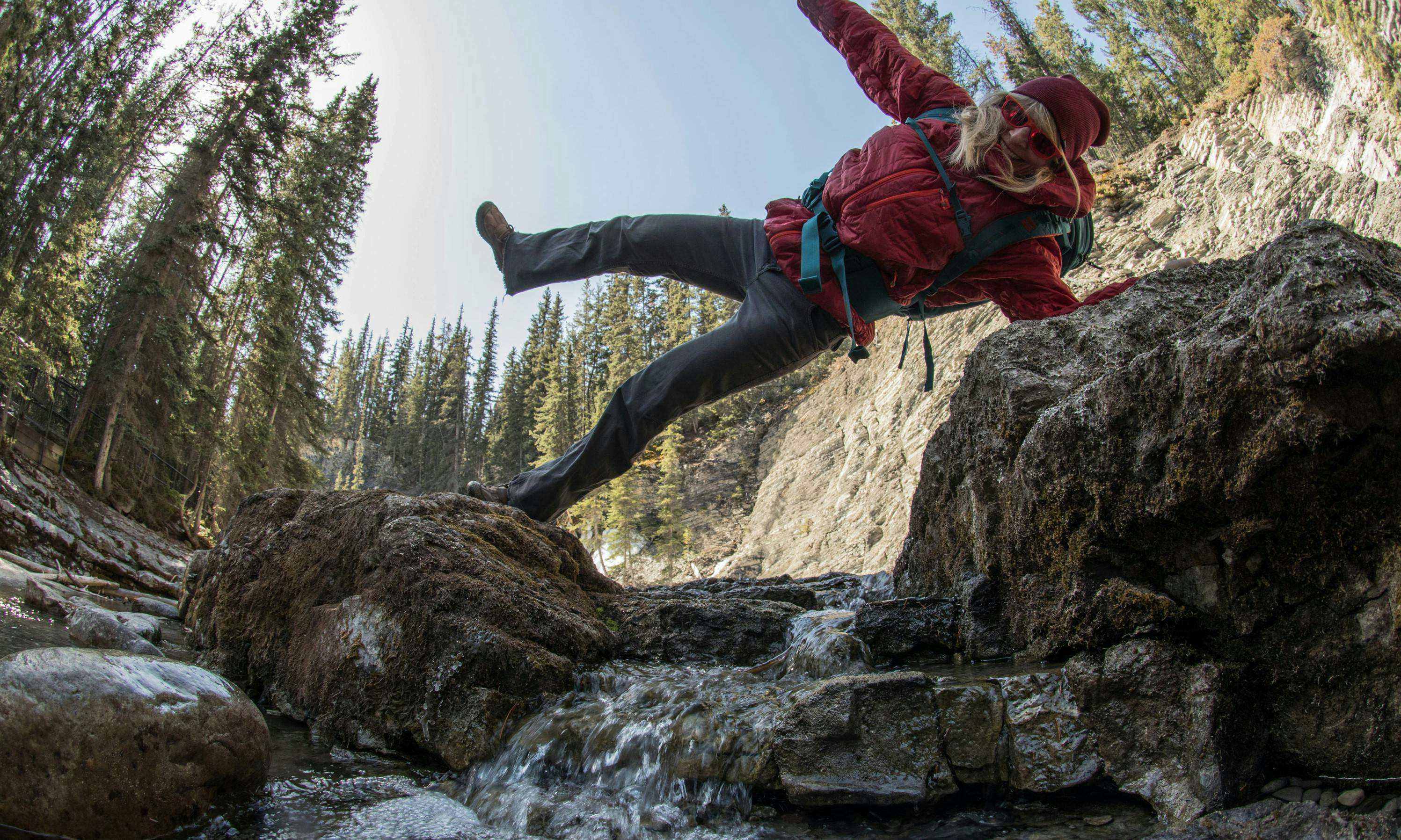 Hiker stretching out over a small creek and having fun