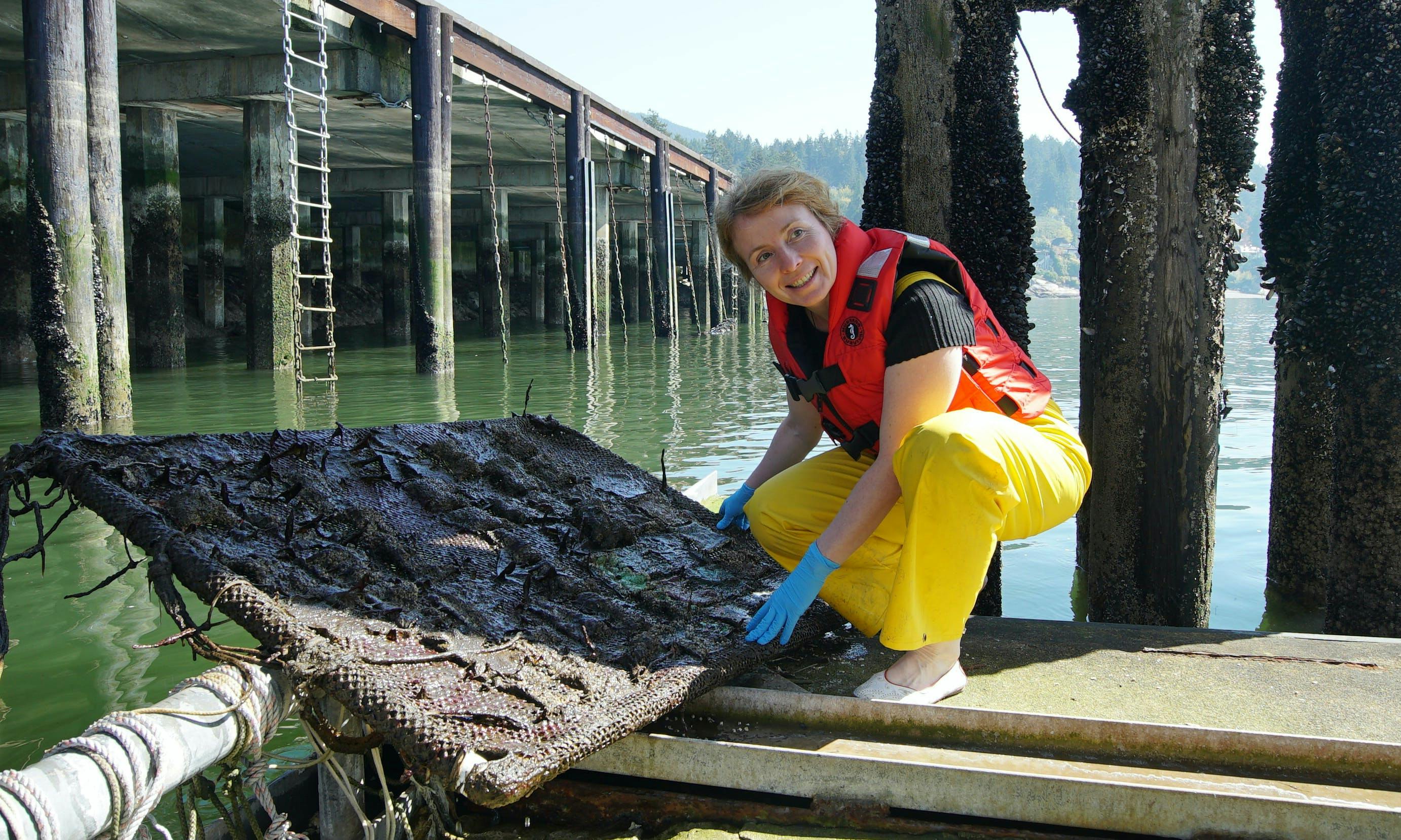 Researcher holding a large sheet of textile samples near the ocean