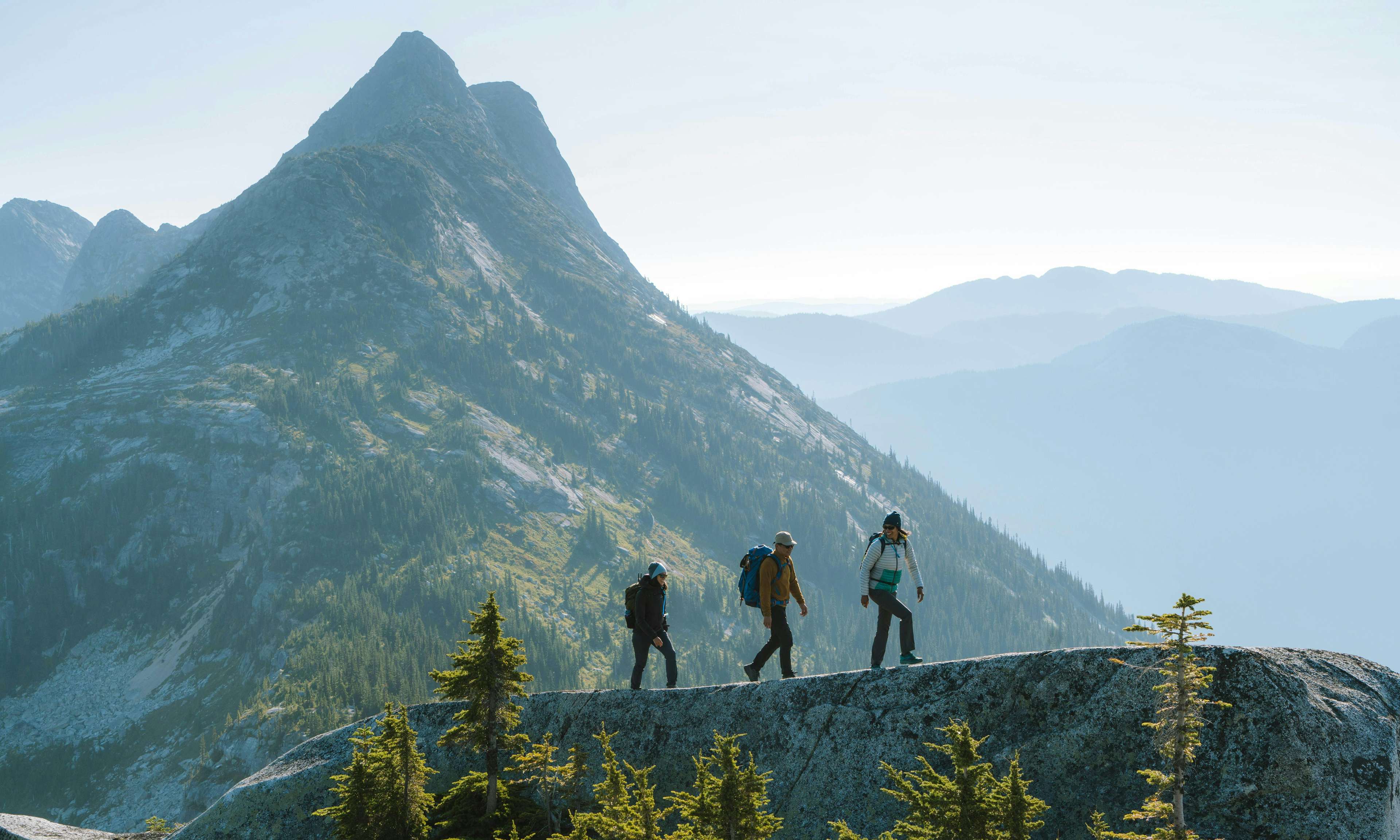 Three hikers on a ridge with a tall peak in the background