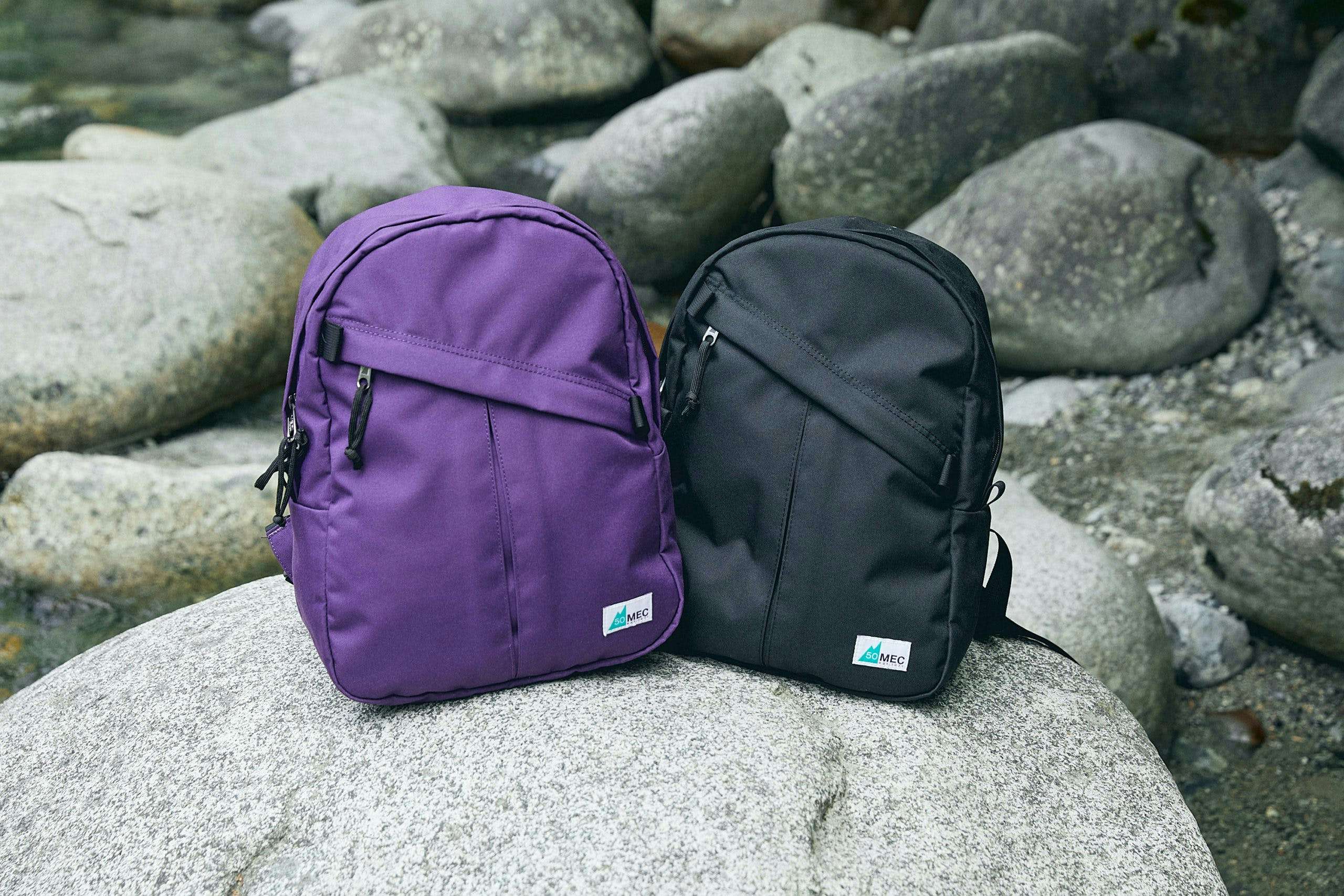 A purple and black MEC Pika Plus pack on a rock