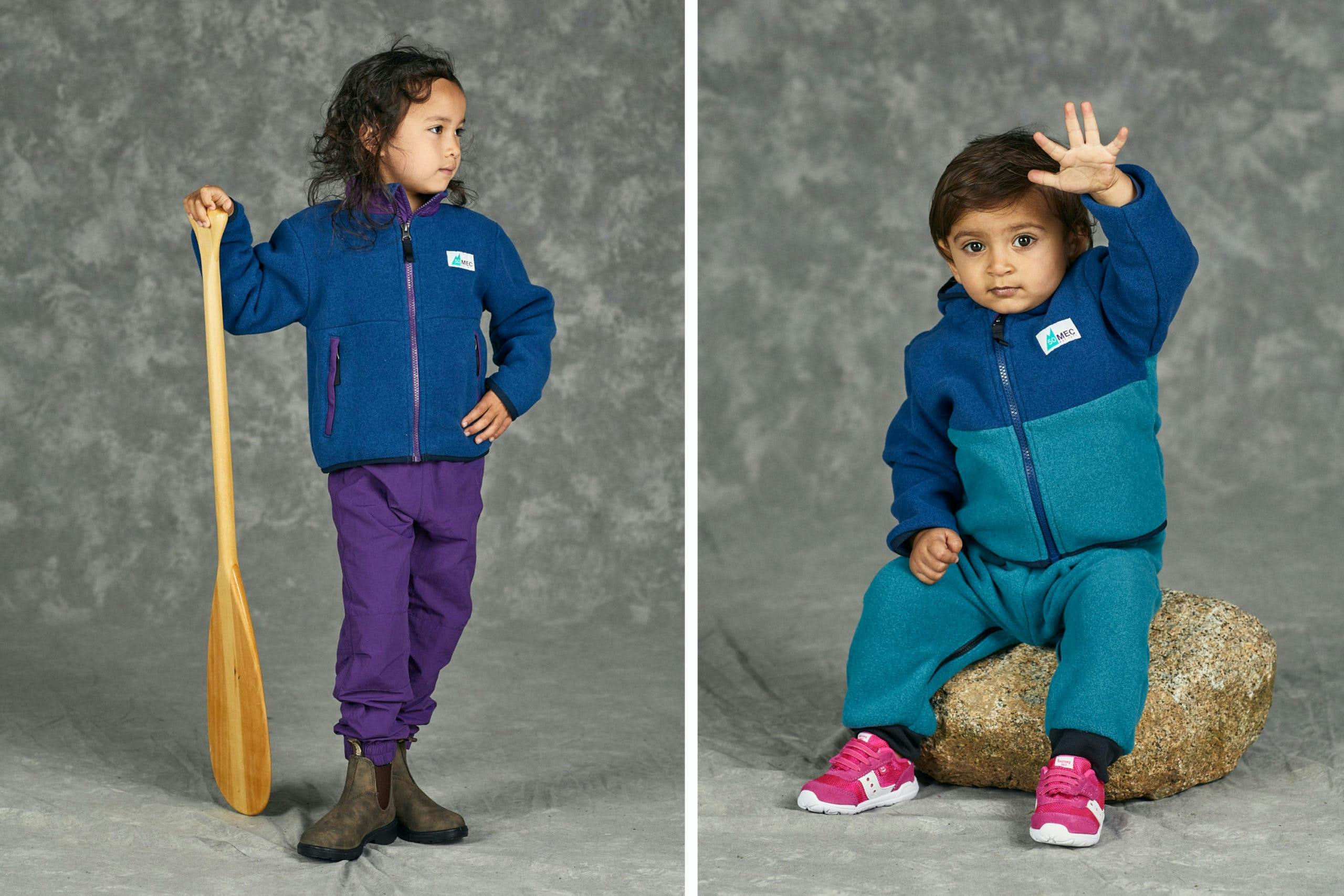 Two young kids wearing blue and teal fleece jackets in a photo studio
