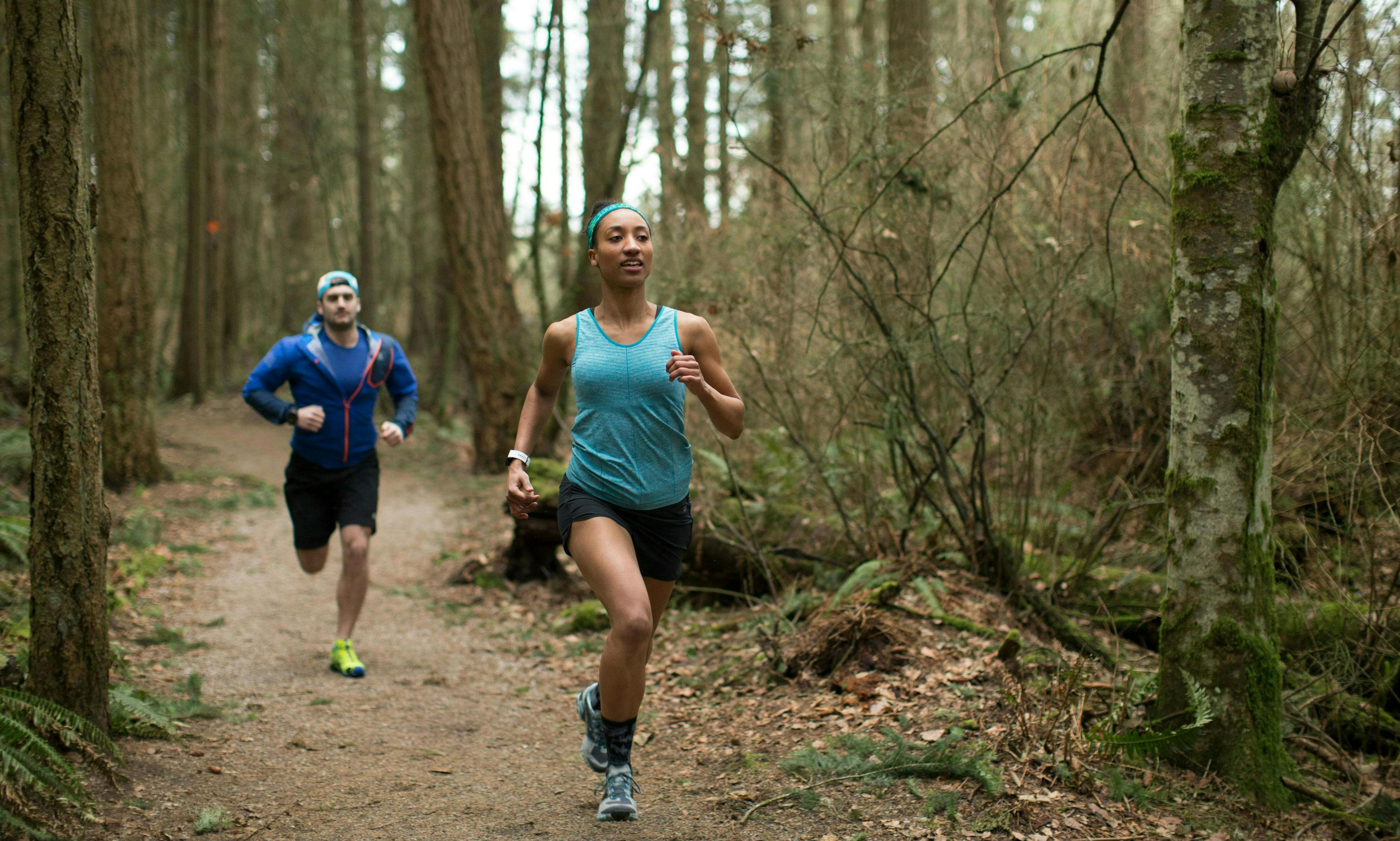 Two trail runners on forest path