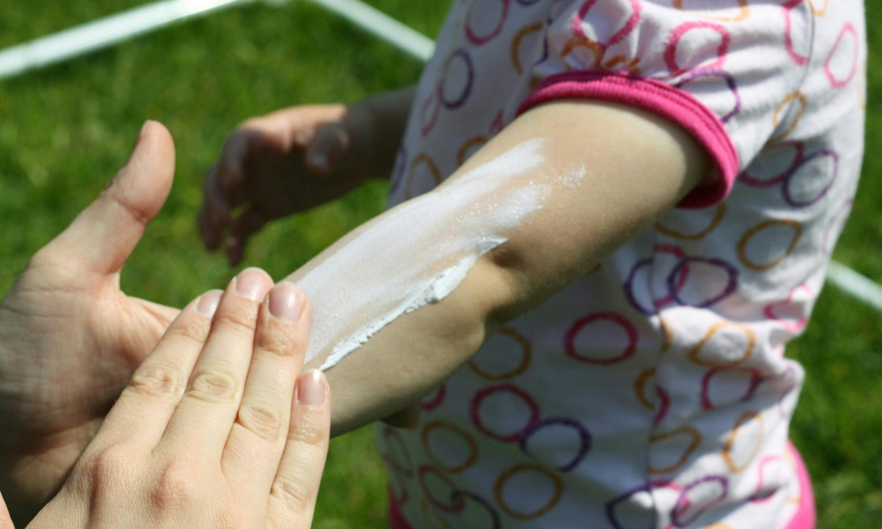 Adult applying sunscreen to a child's arm
