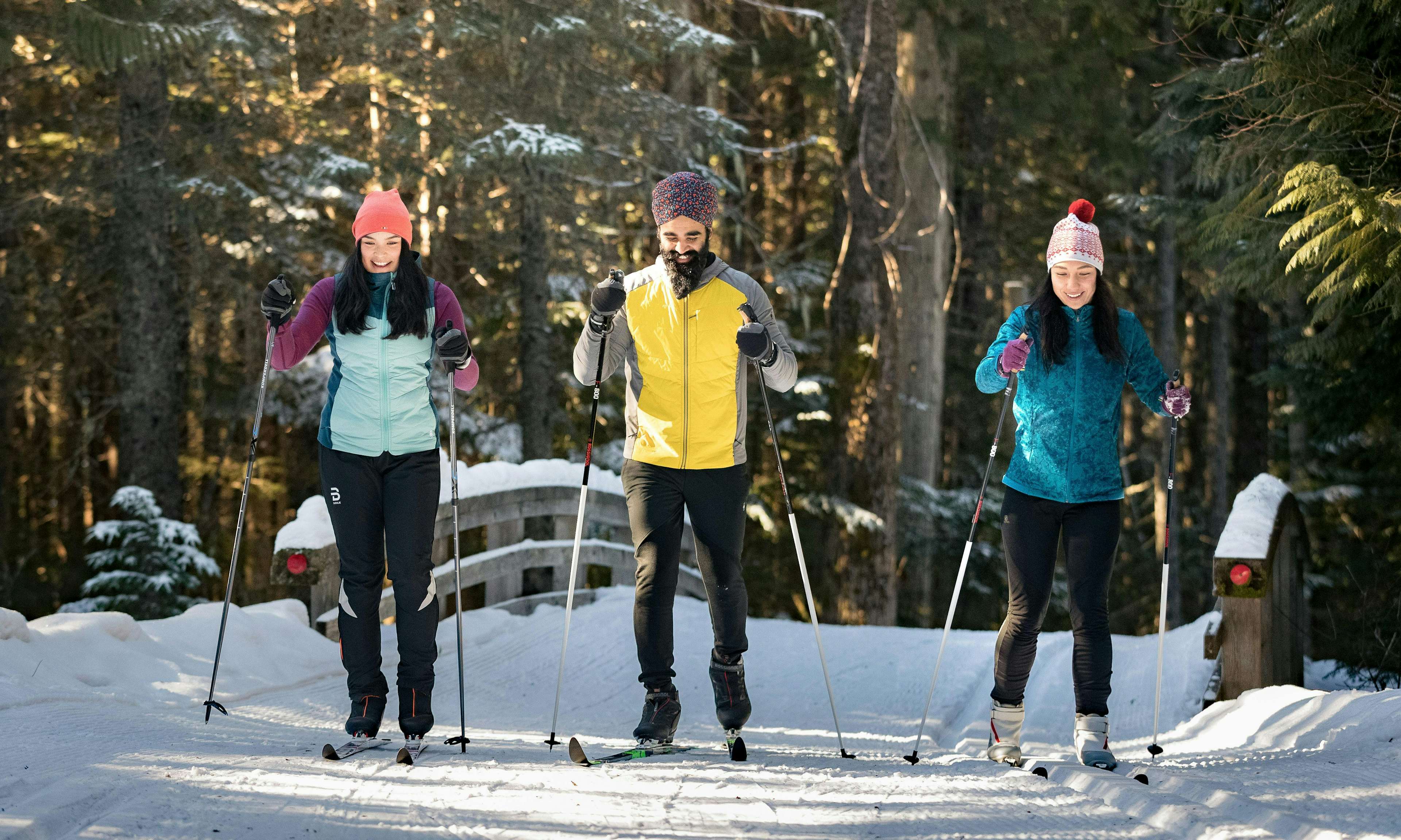 Three people cross-country skiing and smiling