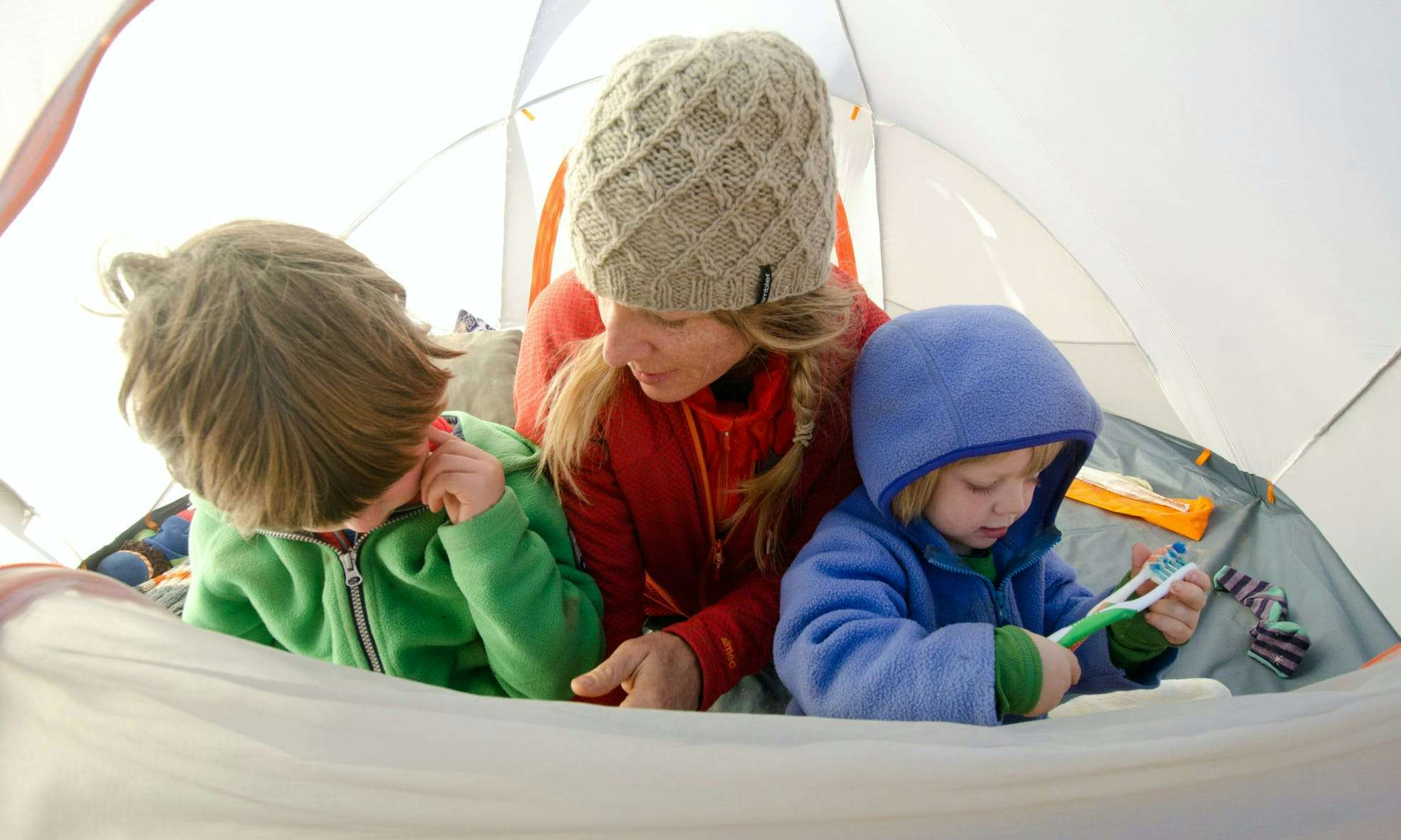 Mom and two young kids in a tent on a camping trip
