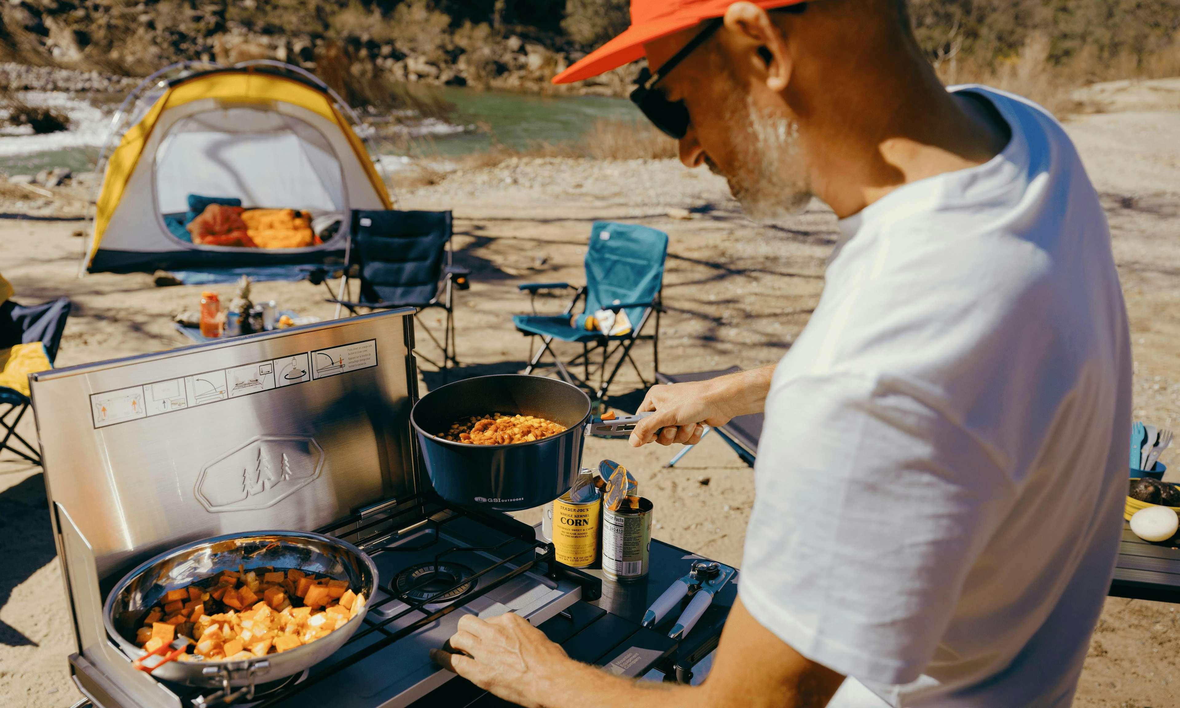 A camper cooking a meal on a camping stove outside. 