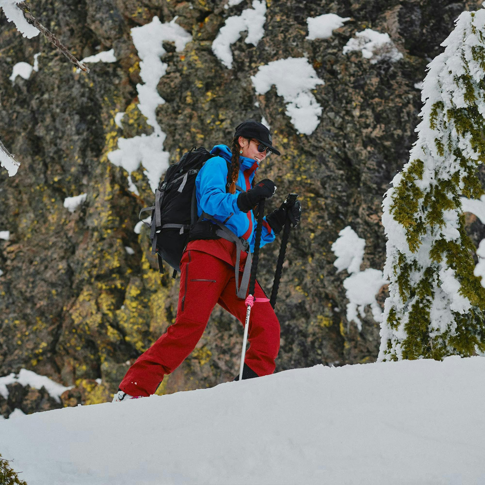 Skier skinning up wearing MEC Apex Icefield Jacket and Salopettes, with mountains behind