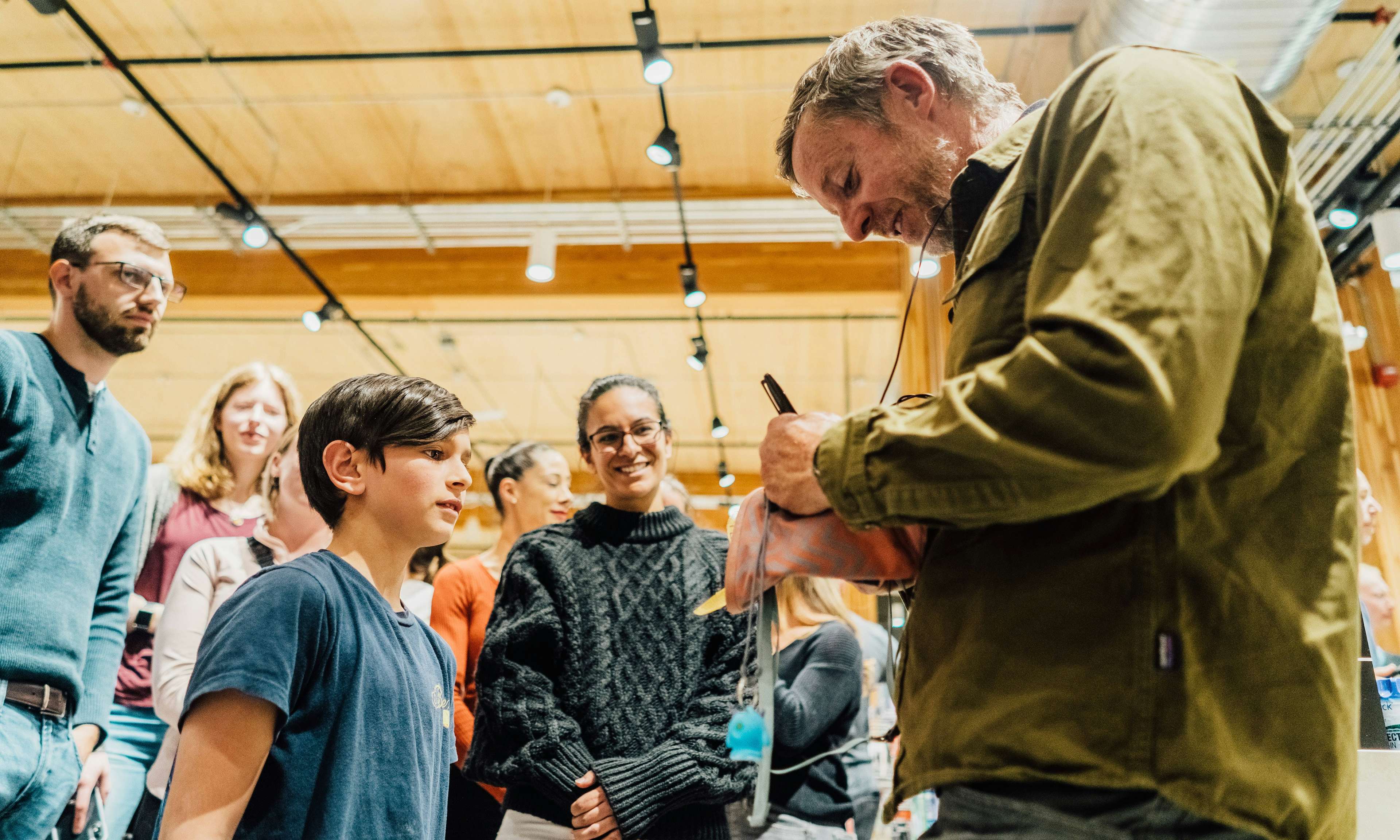 Tommy Caldwell signing a chalk bag for a young climber